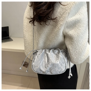 Close-up of silver textured bucket bag with metallic chain and drawstring detail