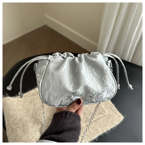 Close-up of metallic silver pleated cloud bag with drawstring and chain shoulder strap