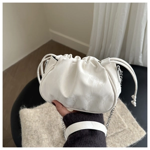 Macro detail of white pleated bucket bag with metal chain strap and soft PU leather texture