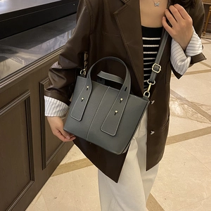 Graublaue Eimertasche aus genarbtem Leder mit goldenen Nieten und Schultergurt