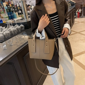 Braune Leder-Eimertasche mit Goldnieten in einem stylischen urbanen Café-Ambiente