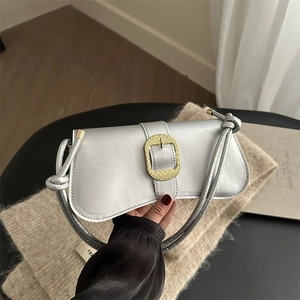 Silver baguette bag with a large gold woven buckle and slim knotted shoulder straps