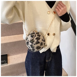 Detail of round leopard print plush evening bag with gold metal ring handles and chain