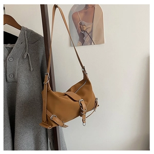 Detail of vintage brown shoulder bag featuring decorative silver metal rings and belt buckles
