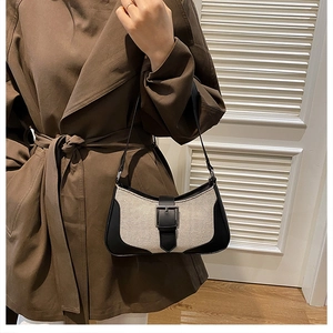 Détail d'un sac demi-lune minimaliste en toile beige et finitions en cuir noir chic