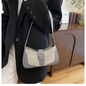 Détail du sac croissant en cuir gris et toile beige avec boucle, porté par un mannequin