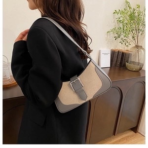 Détail du sac croissant en toile beige et cuir gris porté par un mannequin à l'épaule