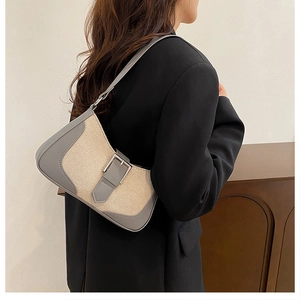 Détail du sac croissant en cuir gris et toile beige avec boucle métallique argentée