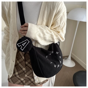 Detail of black corduroy hobo bag with letter embroidery and small round coin purse charm