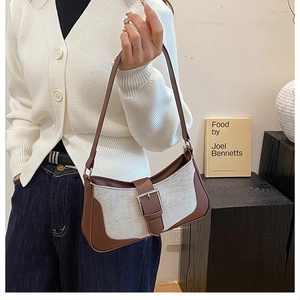 Détail du sac croissant en tweed et cuir avec boucle argentée dans un décor élégant