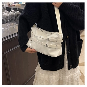 Detail der glänzenden weißen PU-Schultertasche mit Zierriemen und Metallösen