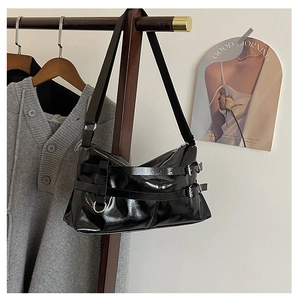 Detail der schwarzen Faltentasche mit silbernen Schnallenriemen und glänzendem Leder