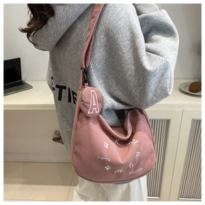 Detail of pink corduroy hobo bag with letter embroidery and small round coin purse charm