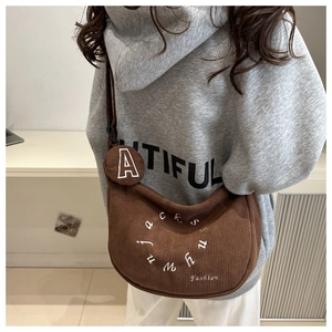 Detail of corduroy hobo bag with embroidered text and small round coin purse