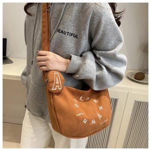 Detail of brown corduroy crescent bag with letter embroidery and mini round coin purse