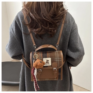 British plaid backpack detail featuring wool texture and plush teddy bear charm