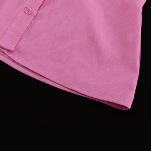Detail of pink cotton shirt hem showing precise stitching and a transparent button