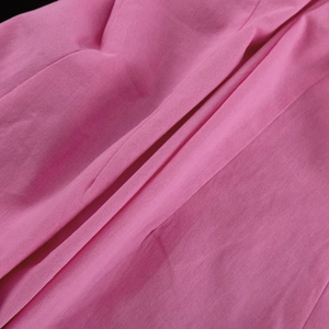 Close-up of pink woven cotton fabric showing natural fiber texture and layered folds
