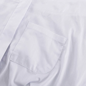 Detailaufnahme der abgerundeten Brusttasche an einer weißen Baumwollbluse für Damen