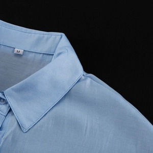 Dettaglio del colletto di una camicia in raso celeste con etichetta taglia M