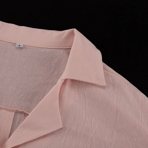 Detail of pink cotton lapel collar with size S tag and textured fabric on casual set