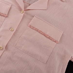 Detail of pink cotton shirt with floral button and raw-edge textured pocket detail