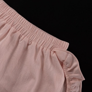 Detail of pink cotton shorts showing elastic waistband and delicate ruffle trim design
