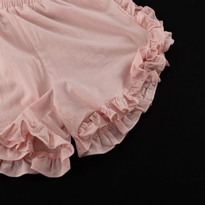 Detail of light pink shorts with elastic waist and ruffle hem in a textured cotton fabric