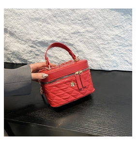 Detail of red quilted mini box bag with golden flower clasp and dual zipper hardware