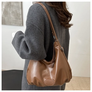 Dettaglio tracolla regolabile e logo goffrato su borsa hobo in pelle marrone