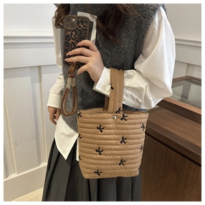 Detail of khaki quilted handbag with black butterfly embroidery and soft padded texture