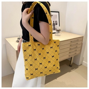 Yellow corduroy tote bag with diamond stitching and black bow patterns on shoulder