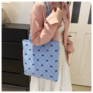 Close-up of light blue corduroy tote bag featuring a cute black bow print pattern