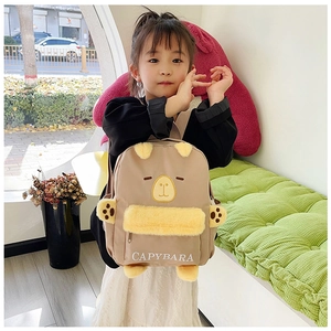 Détail d'un mignon sac à dos en peluche Capybara kaki porté par une petite fille