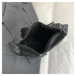 Detailed interior of black pleated shoulder bag showing zipper closure and lining