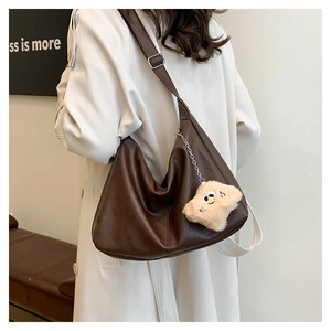 Detail of dark brown crescent bag with grainy leather texture and plush star charm