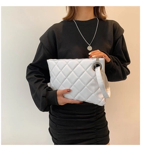Detail of white quilted leather clutch featuring a classic diamond pattern and hand strap