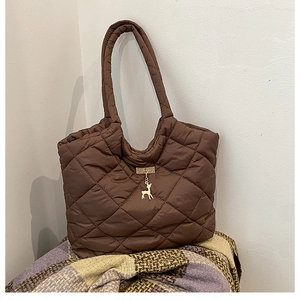 Gros plan d'un sac cabas matelassé marron avec breloque cerf doré en nylon rembourré