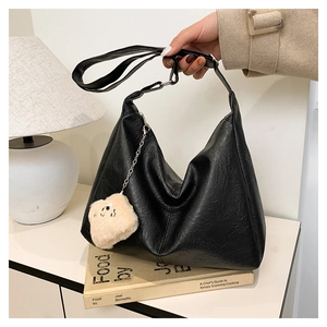 Detail of black faux leather tote with adjustable strap and cute plush bear charm