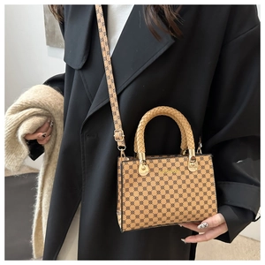 Dettaglio del manico intrecciato e motivo monogramma marrone sulla borsa a tracolla
