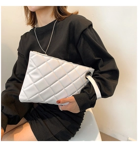 Close-up of white quilted leather chain bag showing luxury stitching and side strap detail