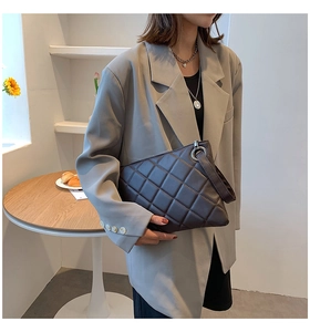 Detail view of a trendy dark brown quilted clutch with wristlet strap and ring detail