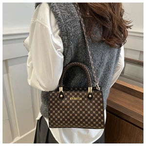 Dettaglio del manico intrecciato e motivo vintage della borsa a tracolla in pelle marrone