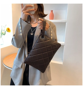 Macro view of dark brown quilted leather clutch featuring elegant metal chain ring and zipper
