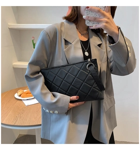 Close-up of black quilted leather texture and silver hardware on a trendy clutch bag