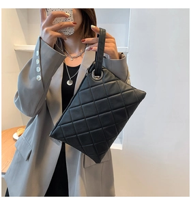Close-up of black quilted rhombus pattern handbag with silver metal ring and handle