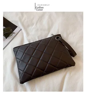 Close-up of brown quilted PU leather clutch bag with matching wristlet strap