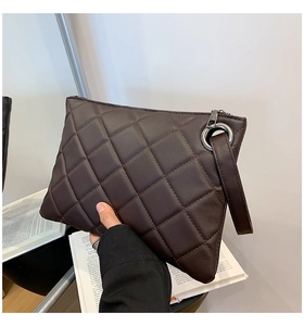 Detail of dark brown quilted clutch with wrist strap and silver zipper closure
