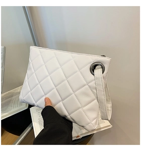 Close-up of white quilted leather clutch bag with elegant wristlet and metal eyelet