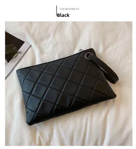 Detail of black quilted leather handbag featuring a wrist strap and metallic ring